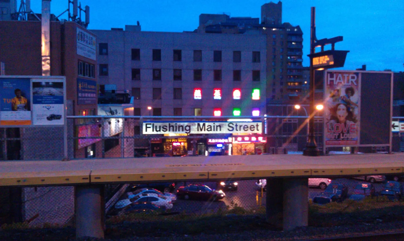 Flushing Main Street station and storefronts at blue hour.