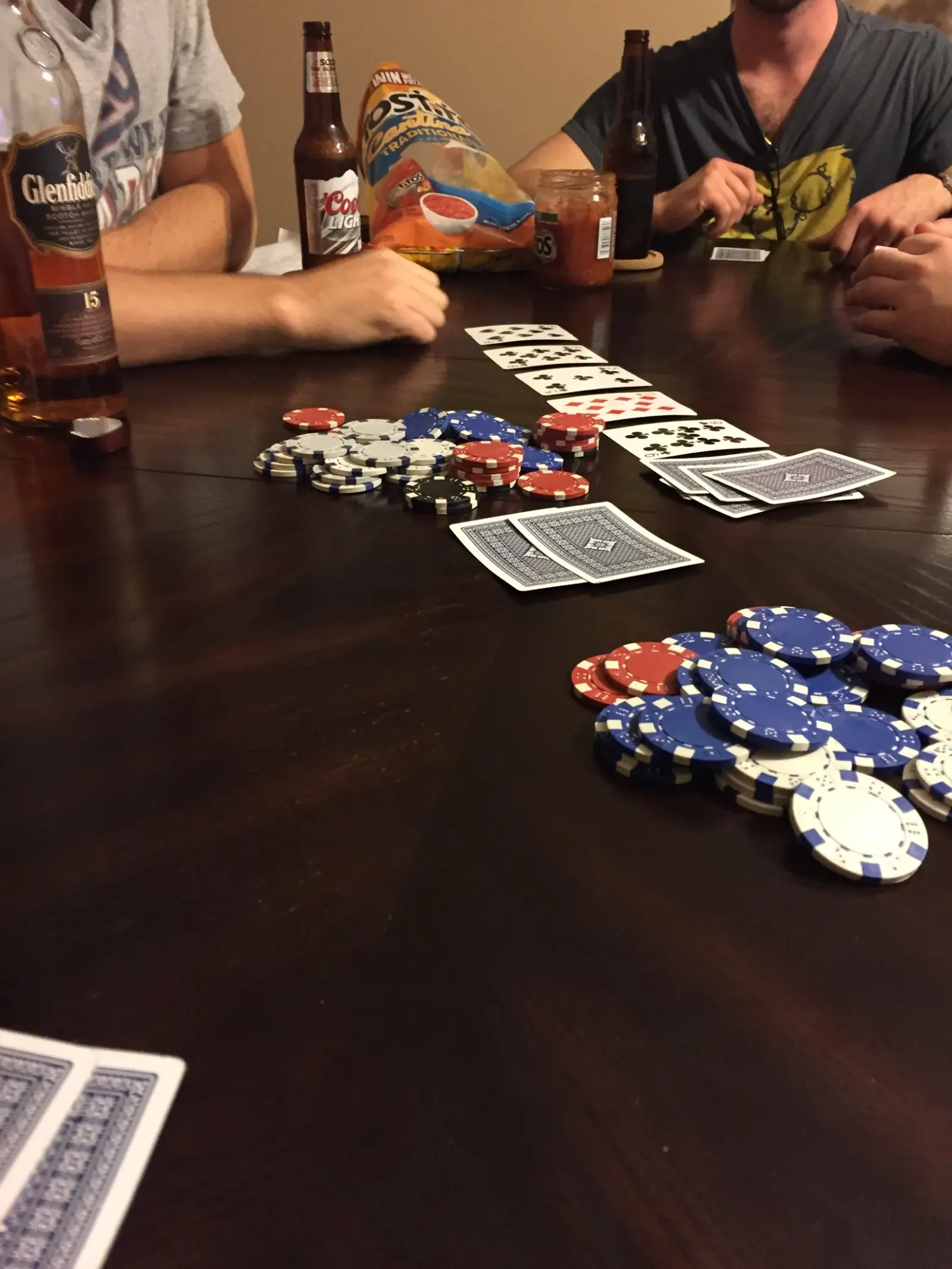 Cards, poker chips, drinks, and friends gathered around a table.